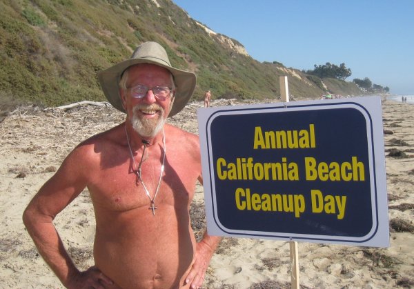 Man on beach with 'California Beach Cleanup Day' sign